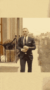 a man in a suit stands on a balcony