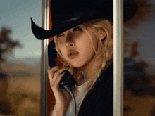 a woman wearing a cowboy hat talking on a phone