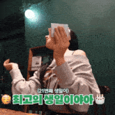 a woman holding a piece of paper in front of her face with korean writing on the bottom