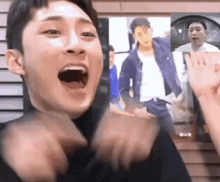 a man is making a funny face with his mouth open while standing in front of a wall .