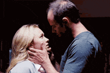 a man is touching a woman 's face while she looks at him