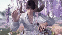 a man in a white shirt is standing under a tree with purple flowers .