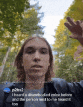 a man with long hair is standing in front of trees and says i heard a disembedded voice before