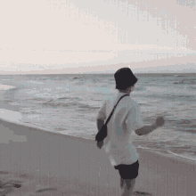 a man in a white shirt and black shorts is running on the beach