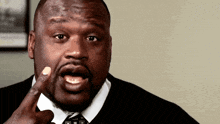 a man in a suit and tie is making a funny face with his finger in his mouth