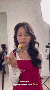 a woman in a red apron is holding a fork and a piece of corn