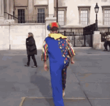 a man in a clown costume is walking down a sidewalk
