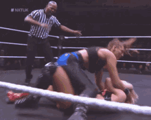 two women are wrestling in a ring with a referee in the background and the hashtag nxtuk