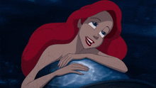 a cartoon of a mermaid with red hair laying on a blue surface