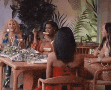 a woman in a red dress is sitting at a table with three other women
