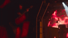 a man is playing a guitar on stage in front of a large screen .