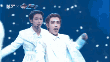 a man in a white suit stands on a stage in front of a sign that says ateez