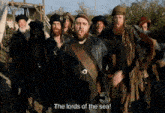 a group of men are standing in a line and one of them says " the lords of the sea "