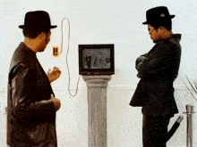 two men are standing in front of a television that has a picture of two men on it