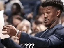 a man in a suit is looking at a piece of paper with the question " what " written below him