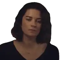 a woman wearing a black shirt and a necklace is looking at the camera