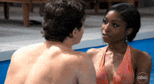 a man and a woman are looking at each other in a swimming pool with abc written on the bottom