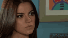 a close up of a woman 's face in front of a painting