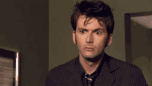 a man in a striped suit and tie looks surprised