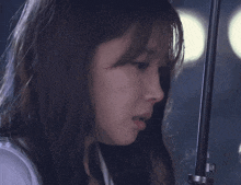 a close up of a woman 's face with an umbrella in her hand