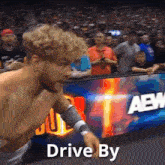 a shirtless wrestler in front of a crowd with the words drive by written below him