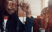 a man with dreadlocks wearing sunglasses and a gold watch