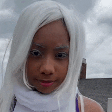 a woman wearing a white wig and a white scarf looks at the camera