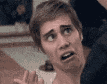 a man is making a funny face while looking up at something .