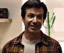a man wearing a plaid shirt is smiling and looking at the camera .