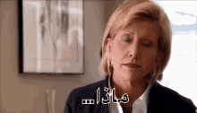 a woman with her eyes closed is sitting in front of a framed picture and a sign in arabic .