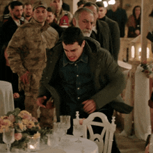 a group of men are standing around a table with a white chair in the middle