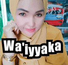 a woman wearing a hijab and a yellow shirt with the words wa ' iyyaka on it