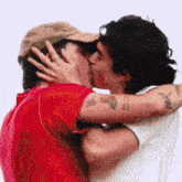 two men kissing with one wearing a hat and the other wearing a red shirt