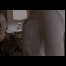 a man and a woman are standing next to each other in a room with a lamp .