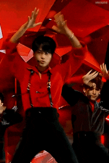 a man in a red shirt is dancing on a stage with his arms in the air .