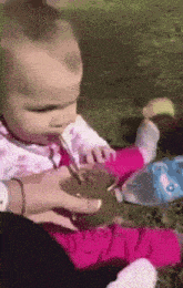 a baby is drinking from a cup with a spoon