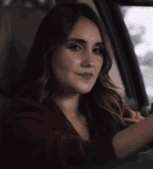 a woman is sitting in the driver 's seat of a car and smiling