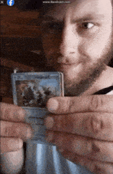 a man with a beard is holding a pokemon card with a picture of a penguin on it