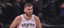 a basketball player with a beard is wearing a white jersey with a proust logo on it .