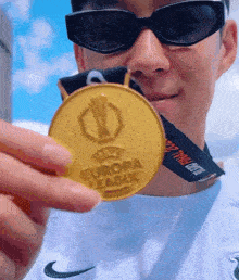a man wearing sunglasses is holding a gold medal that says europa league on it