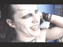 a woman wearing a choker and bracelets is smiling and looking at the camera
