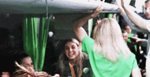 a woman in a green shirt is standing in a crowd of people on a bus .