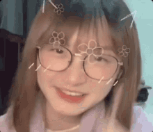 a girl wearing glasses and a purple shirt is smiling .