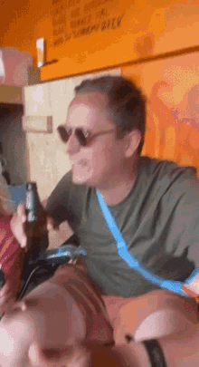 a man wearing sunglasses holds a beer bottle