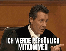 a man in a suit and tie is sitting in a courtroom with the words ich werde personlich mitkommen above him .