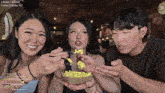a man and two women are eating popcorn in front of a screen that says today 's subs at the top