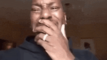 a man with a ring on his finger is covering his mouth with his hands .