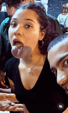 a woman sticking her tongue out next to a man in a crowd