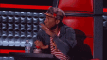 a man is sitting in a chair with his arms outstretched in front of a red wall .