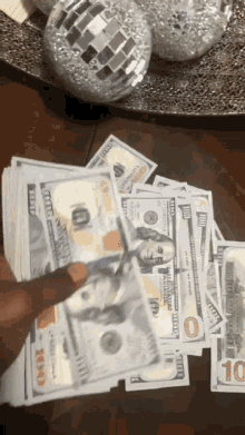 a person is holding a stack of 100 dollar bills on a table